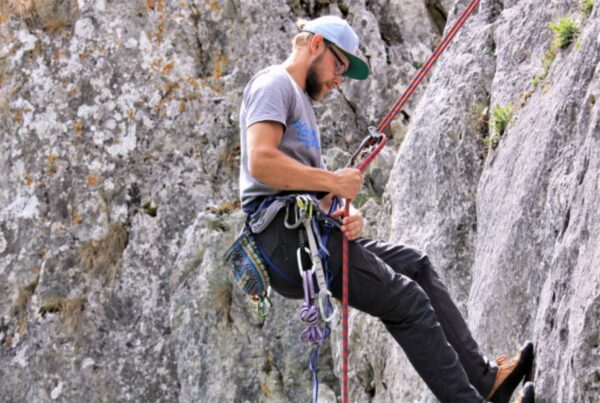Themenbild eines Kletterers, der sich an einem Felsen abseilt.