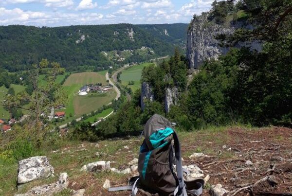 Bild von einem Rucksack auf einem Hügel mit Blick in ein Tal.