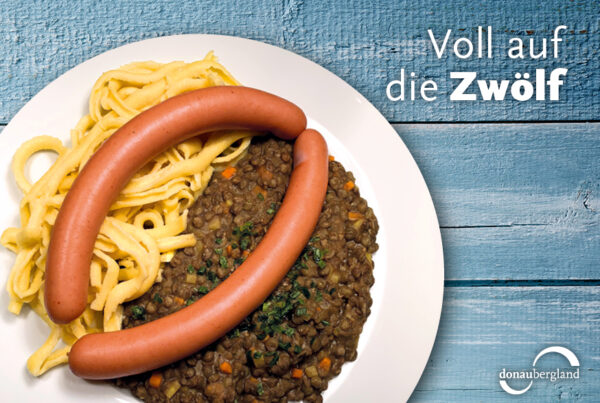 Donaubergland Postkartenmotiv mit Teller auf dem Linsen, Spätzle und ein Paar Saitenwürste sind.