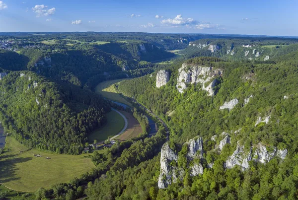 Luftbild über ein felsiges und bewaldetes Tal durch das sich die Donau schlängelt
