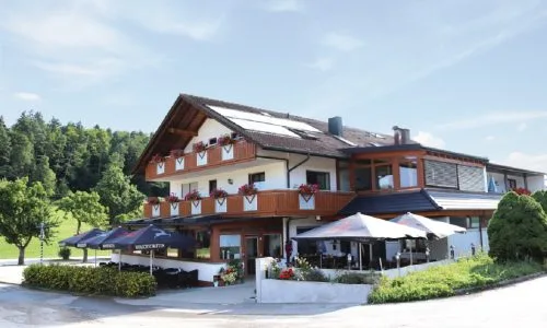 Bild von Landgasthof Waldeck in Dürbheim, mit Blumenkästen am Balkon und aufgeklappten Schirmen auf der Terrasse