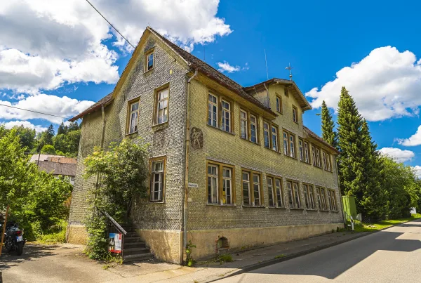 Bild eines alten Hohnergebäudes in Egesheim mit zugewachsener Eingangstreppe und die Fassade ist komplett mit Schindeln verkleidet.